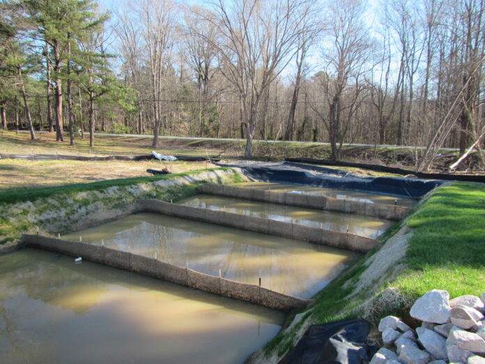 Sediment basin with porous baffles and a skimmer on a roadway construction project.