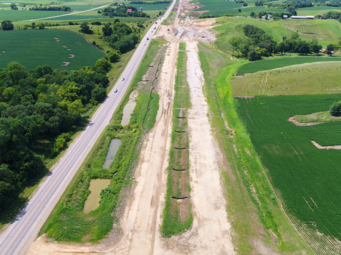 1. Aerial image of U.S. 30 Highway construction in Tama County, Iowa, USA, that shows the existing two-lane route and the adjacent expansion, which includes four travel lanes, a median and shoulders.